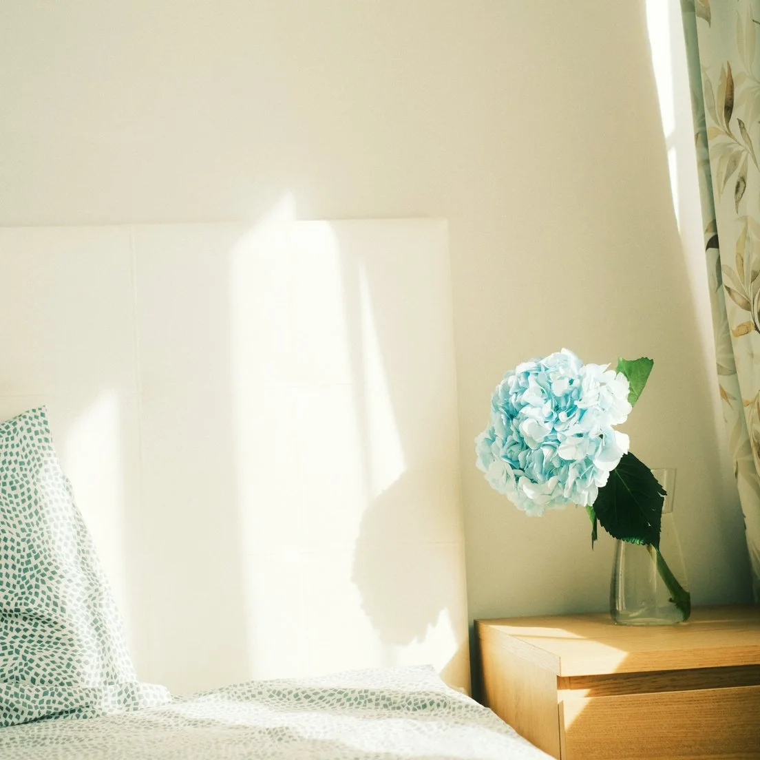 Fresh flowers by a made bed